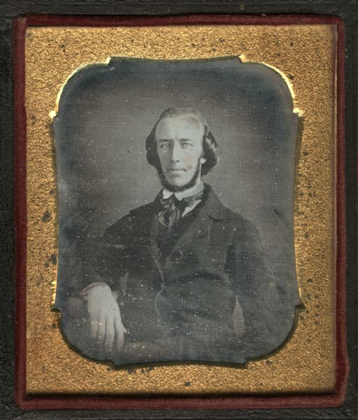 Sixth plate daguerreotype of Frederick J. Starin. Half length portrait, facing forward with right forearm on table, wearing suit and tie with collar turned down, and chin whiskers. Hand-coloring on cheeks, lips, and chin. 