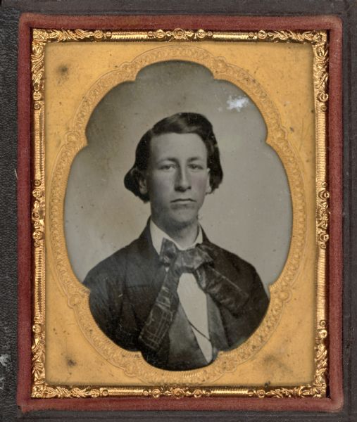 Ninth plate ambrotype of Sinclair W. Botkin, University of Wisconsin Class of 1857. Quarter-length portrait, facing forward. He is wearing a suit and patterned tie with long tails. Hand-coloring on cheeks. 