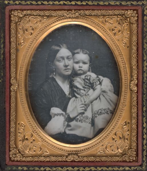 Sixth plate daguerreotype of Frances Adams and her daughter. Frances is holding the child's face to her cheek. The child is wearing a light-colored short sleeve dress with dark trim. Hand-coloring on cheeks. 