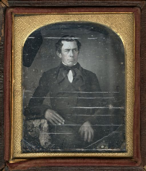 Sixth plate daguerreotype of Doctor Cuyler Tanner. Three-quarter length portrait, seated, facing forward, wearing double-breasted suit with stand collar and long-tailed tie. His right forearm rests on a cloth-covered table. His hair is combed forward over the temples. Hand-coloring on cheeks. 
Tanner was born June 12, 1792 in Stephentown, NY, and died October 7, 1857, aged 65. He had two sons and five daughters. One son, Ford, came to Whitewater, Wisconsin in 1851. On son, Kirk, came to Milton Junction, WI in 1858. One daughter, Harriet, came to Waukesha, Wisconsin in 1841. One daughter, Julia Ann, married a school teacher in 1842. 