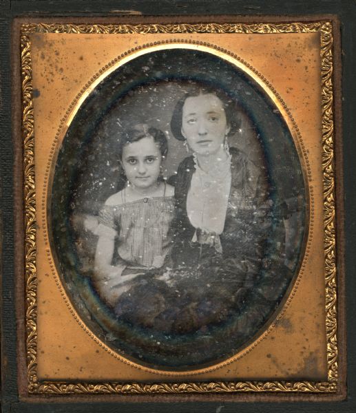 Sixth plate daguerreotype of Florella P. and Helen A. Burrows, sisters of George Baxter Burrows of Madison, Wisconsin. They are seated, facing forward. The elder sister is wearing a dress of fine fabric, white blouse with lace collar, brooch, and earrings. The younger sister is wearing a striped dress that is off-the-shoulder, earrings, and a necklace. Hand-coloring on cheeks. 