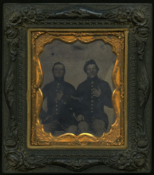 Sixth plate ferrotype/tintype of two Civil War soldiers in uniform, seated, both with left hands in hidden hand pose with jackets buttoned. 
