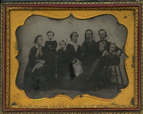 Half plate ambrotype of William D. Ash and his family. Left to right: 1. Helen Mar, later Mrs. E.P. Lamb in Roberts, Wis. 2. William H. Ash, later of Roberts, Wis. 3. Adelbert John, later Dr. A.J. Ash. 4. Mrs. Elmira (Putnam) Ash. 5. Leila, later Mrs. George Laing, Fond du Lac, Wis. 6. William D. Ash, at this time a farmer in the town of Oakfield, Fond du Lac County, Wis., and later of Brandon, Wis., where he died. 6. David, who died as a child. 
