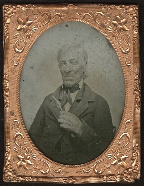 Sixth plate ambrotype. Waist-up portrait of Doctor John M. Henderson, seated, facing forward with torso turned slightly left. He is wearing a suit and tie, and is holding his eyeglasses with his hand on his chest. His eyes may have cataracts. He was an early Wisconsin settler, and 78-years-old at the time of the portrait.