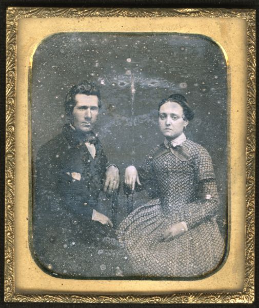 Sixth plate daguerreotype of Draud Schellem (or Schelleran) and his wife. They are sitting, facing forward, but turned slightly toward each other, with wrists resting on the backs of their chairs. He is wearing a suit, bow tie, and pocket handkerchief. She is in a print fan front dress with high white collar and wide ribbon crossed and held by a brooch. 