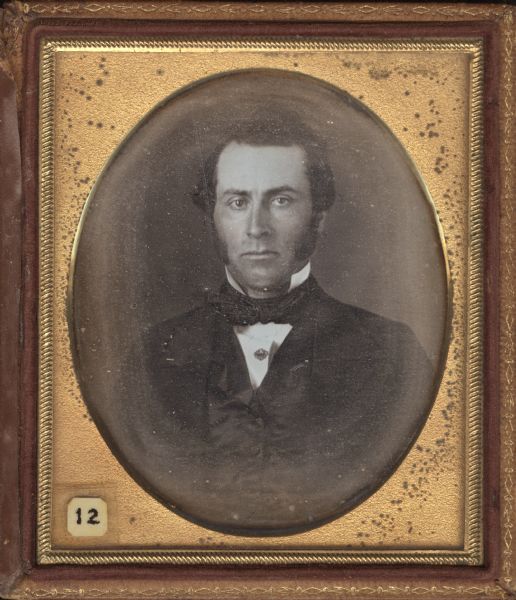 Sixth plate daguerreotype of Dr. Daniel Derendorf. Quarter-length portrait, facing forward. He is wearing a suit, cravat, and stand collar, with sideburns, and his hair in a slight topknot. Hand-coloring on cheeks. 