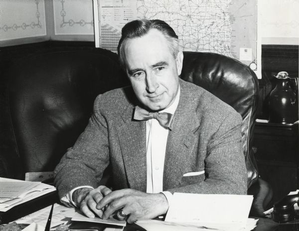 Casual portrait of Vernon Thomson seated at his desk in the State Capitol. A map of Wisconsin is mounted on the wall behind his desk. Thomson served as the Attorney General of the State of Wisconsin from 1951-1957. He then became the Governor of Wisconsin from 1957 to 1958. Following his tenure as Governor, Thomson served in the U.S. House of Representatives from 1961 to 1974, representing the 3rd district of Wisconsin. Thomson belonged to the Republican Party.
