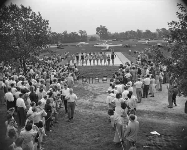 Elevated view of crowd at E.H. Myrland's Farm's Sky Lodge at the bathing beauty contest at the dedication of a new swimming pool at the resort which opened in the fall of 1948. More than 300 airplanes and 1500 persons attended. The three finalists of the contest were Mrs. Dick (Mary Jo) Bennett, Middleton; Evaline Stange, Beaver Dam; and winner, Rosemary Schwebs, Neenah.