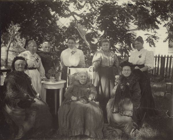 Outdoor group portrait of the Sauk City Humanist Ladies Aid. Standing left to right: Mrs. Crusius, Mrs. Kuoni, Mrs. Mueller, O. Meyer, Mrs. Schmiedhofer. Seated: Mrs. Naffz, Mrs. Lenz, Mrs. Cunradi