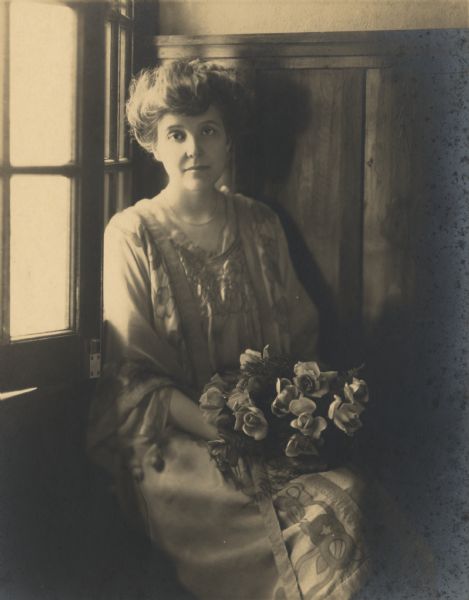 Indoor portrait of Zona Gale Breese holding a bouquet of flowers.