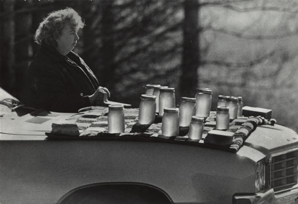 Mrs. Gilbert Ward waiting for honey customers along Highway 501. Jars of honey are displayed on a blanket on the hood of her car.