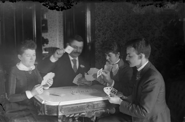 Mr. and Mrs. Frederick L.G. Straubel playing cards in a parlor with Mr. and Mrs. Kemnitz