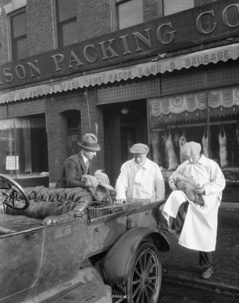 Three men inspecting chickens in front of the Madison Packing Company located at 307 West Johnson Street. One of the men is identified as Norbert J. Noltner.