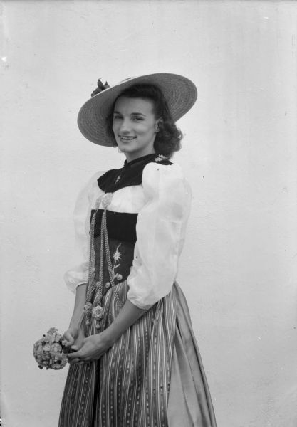 Portrait of a woman in a Swiss costume holding a bouquet of flowers.