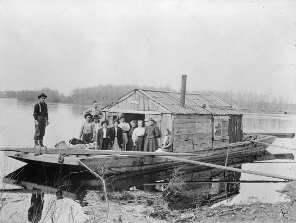 Group of people on a wanigan, the "Dancing Annie," used by Chippewa Lumber and Supply Company near Eagle Rapids. A wanigan is a floating office and supply store used by the logging companies.