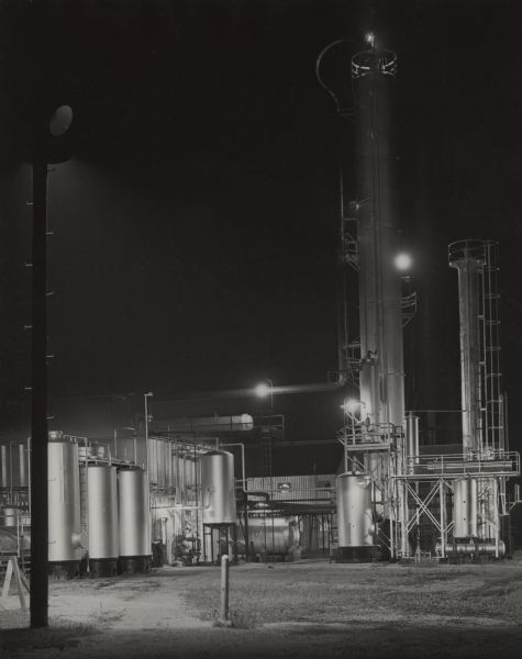 An oil refinery at night illuminated by overhead lights.
