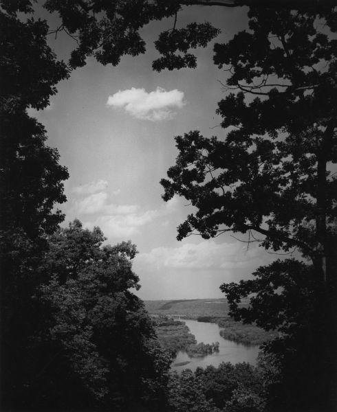 Elevated view of the Wisconsin River from Wyalusing State Park, framed by trees. There is a bridge over the river in the distance.