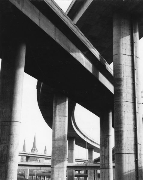 A view of the underside of a highway interchange. Steeples of a church are in the background.
