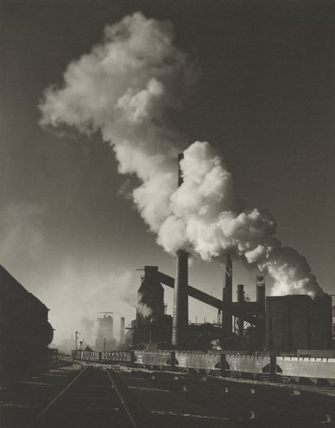 Solvay Coke and Gas Company with railroad train and tracks, smoke billowing upward. The company was opened in 1906 and closed in 1983.