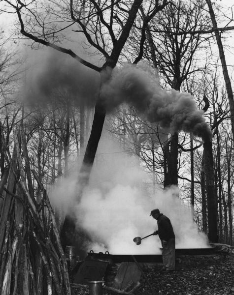 Steam and smoke billow as a man is boiling maple syrup on the Harvey Blue farm.                                                  