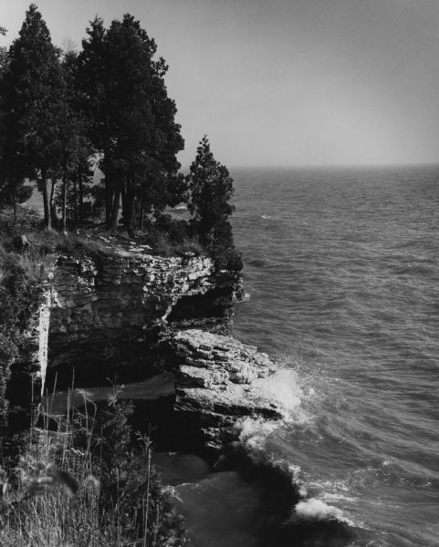 Pine trees at the edge of the rocky shoreline in High Cliff Park on Lake Michigan.