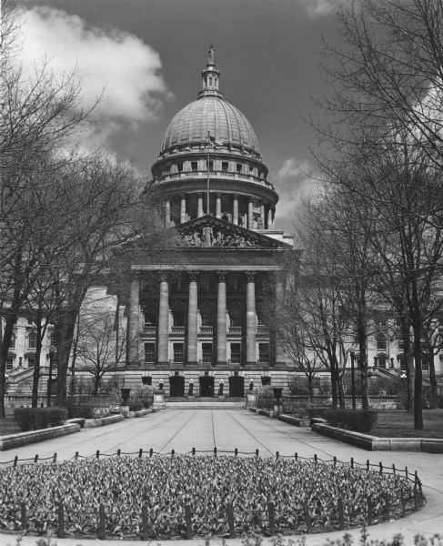 The 4th Wisconsin State Capitol, built in 1906-1917. In the foreground is a large, round bed with a display of tulips.