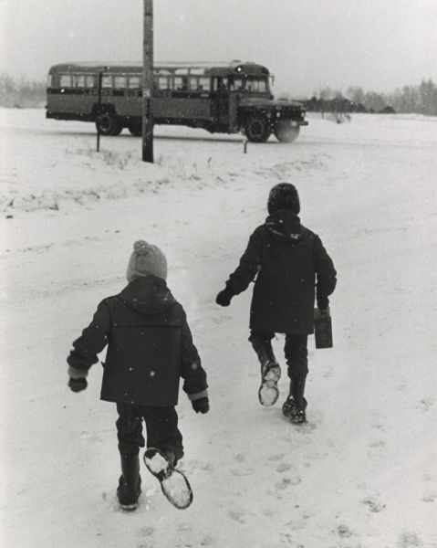 Children running to the school bus during a light snow fall.