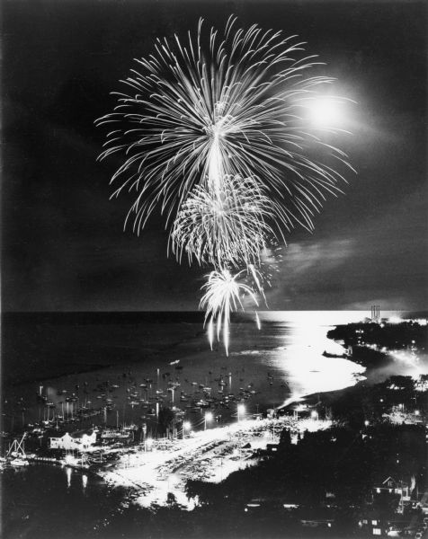 Aerial view of fireworks over Lake Michigan. Boats are moored in the harbor for a good view.