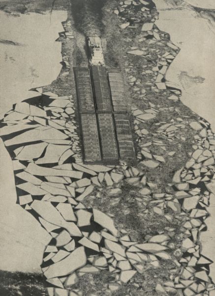 Towboat pushing barges through ice on the Mississippi River as winter closes shipping traffic. Elevated view shows broken ice surrounding the barges, creating a mosaic pattern. Title on back of print: "Winter Barges In".