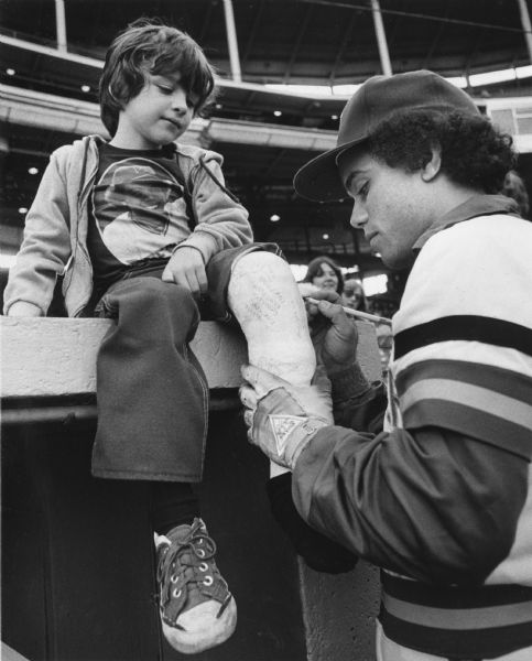 Sixto Lezcano signing a young fan's cast at Milwaukee County Stadium. The boy's tee-shirt has Sixto's portrait on it. Lezcano spent six seasons with the Milwaukee Brewers.
