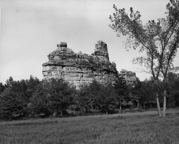 Castle Rock, surrounded by trees and a meadow. The geological feature is near Volk Field Air National Guard Base.