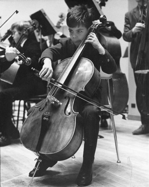 A young cellist concentrating while playing his instrument.