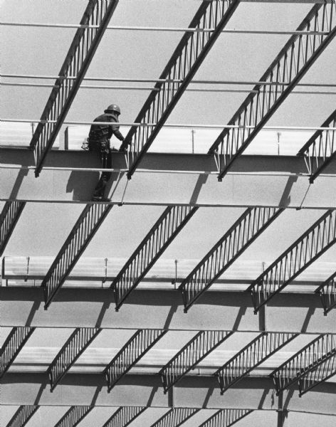 A construction worker is perched on top of steel beams during construction of a large building.