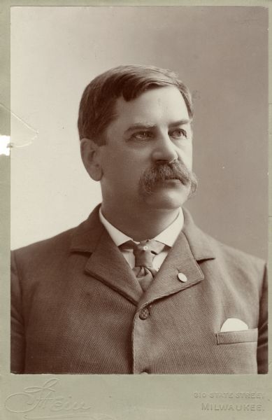 Quarter-length portrait of William H. Upham, Wisconsin's 18th governor. He is wearing a suit, necktie and tie pin.
