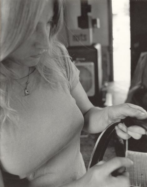 Close-up of a woman working on a strap of leather in a shop.