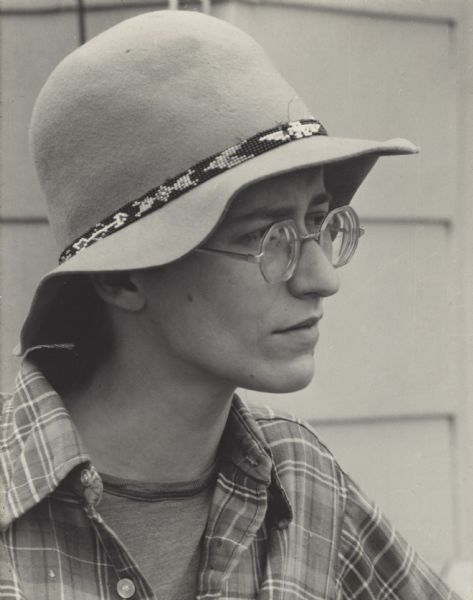 Head and shoulders portrait of a young woman named Karen Jaster. She is wearing eyeglasses, and a broad brimmed hat with a beaded headband.