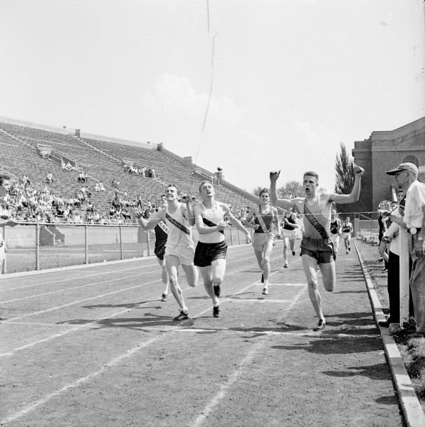Finish line of the second section of the Class A 440 yard dash at the 1953 state high school track meet held at Camp Randall Stadium.
Shown (L-R) are Sam McGinnis, Wauwatosa (4th); Richard Henske, Milwaukee Washington (3rd); Dick Hackett, LaCrosse Central (2nd); Don Hanson, Racine Park (5th); and Stephen Pralle, Sheboygan North (1st).