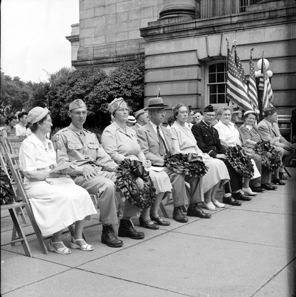 Madison observed Memorial Day with a parade and three memorial services. A Memorial Day address by Assemblyman Elmer L. Genxmer was followed by a wreath ceremony at the south entrance to the Wisconsin State Capitol. A group of participants in the wreath ceremony are, left to right: Mrs. Everett Kissam, Woman's Relief Corps; Cpl. Seiler Ong; Leone Morrissey, Veterans of Foreign Wars Auxiliary; Capt. Joseph W. Bollenbeck, Military Order of the World Wars; Elizabeth Thale, American Legion Auxiliary; Milton Fulda, American Legion; Mrs. Howard Kuhlman, United Spanish War Veterans; Commander Joseph Wittman; Magdalen Vetter, Service Star League; and Donald Rathbun, Veterans of Foreign Wars.