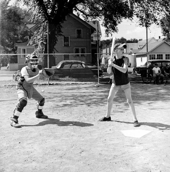 A youth baseball player awaits the pitch. Shown (left to right) are: catcher Ronnie Millard and batter Dean Adams.