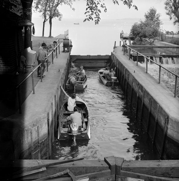 Boaters passing by through the Tenney Park lock in three motor boats.