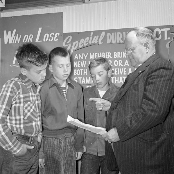 Clarence H. Beebe, executive director of the Four Lakes Council Boy Scout drum and bugle corps, explains application blanks to prospective members Jim Greene, Route 4, Madison, Bobby Recob, 826 Terry Place, and Phil Lindemann, 2546 Upham Street.