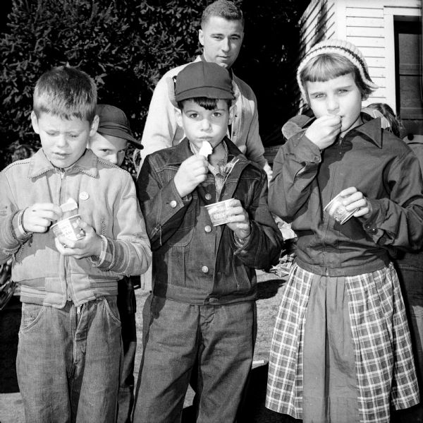 Four Lapham School students and an adult eating ice cream from a paper cup at the end of a tour of Bowman Farm Dairy on Fish Hatchery Road.