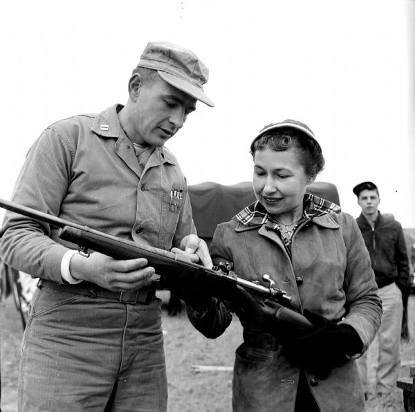 Captain Leo Lewis, inspector-instructor at the Naval-Marine Corps Reserve Training Center in Madison, explains the bolt operation of a rifle to Mrs. Paul Biehl of Libertyville, Illinois. This was part of a gun safety session at the Winnequah Gun Club near Lodi.