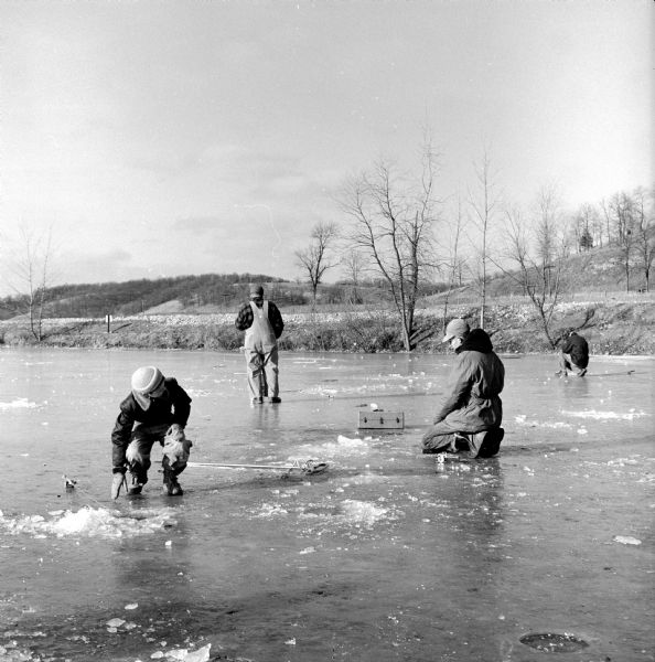 Three people ice fishing on Salmo Pond near Black Earth.