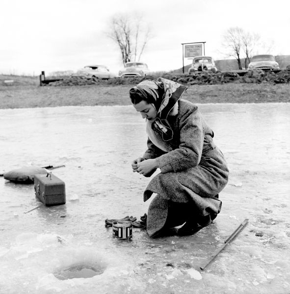 Mrs. Arthur Fecht, Highland, attaches bait to her line while ice fishing on Salmo Pond near Black Earth.