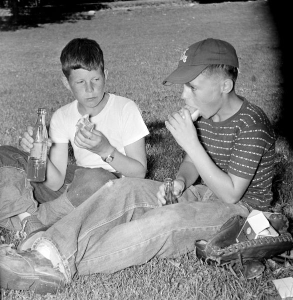 Madison Newspaper, Inc, hosts a picnic for newspaper carriers as a special recognition to the boys, each an individual businessman, who carry the papers in any weather. Participants Gregor Isackson (left) and Bill Males (right) enjoy a hot dog and a bottle of pop.
