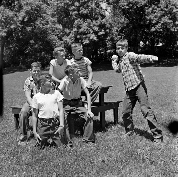 Madison Newspaper, Inc. hosts a picnic to recognize newspaper carriers, each an individual businessman, who carry the papers in any kind of weather. Gregor Isackson, Tom Gorman, Alan Braeger, Lawrence Gehri, and Leon Cloud are watching Peter Pauley throwing the ball during the baseball throwing contest.