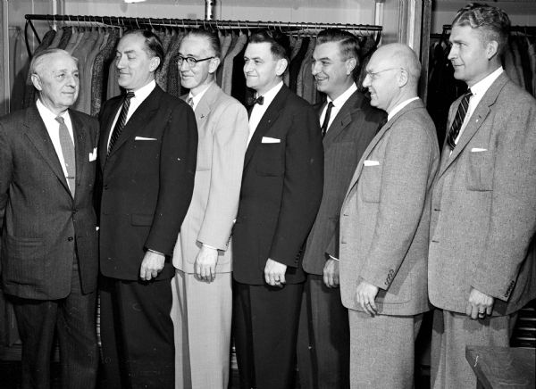 The Spoo and Son men's clothing store is being turned over by its president, Erwin M. Spoo (left), to six employees. They include, from left to right, E. Wesley Holmquist, Jack Hilgers, Eric Lutterman, William Dyhr, Edward Hartung, and Maynard Moss.