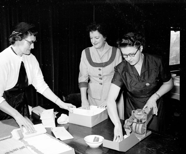 Women of the Elk prepare materials for distribution for the 1954 Christmas seal drive honoring the 50th anniversary of the National Anti-Tuberculosis Association. Shown stuffing envelopes are, (left to right): Mrs. William Wolff, 2700 Gregory Street; Mrs. F.E. Nordeen, 713 Huron Hill; and Mrs. F.D. Beaudette, 3732 Sargent Street.