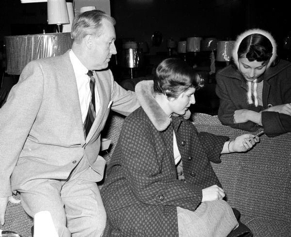 West High School seniors, Geraldine Doran, right, and Gretchen Ihde look at sofas with Tom Rennels, a salesman at the Black Furniture Store, as part of an assignment for their Problems of Democracy class.  Members of the class were assigned to research a financial issue of an "average" Madison couple. 
